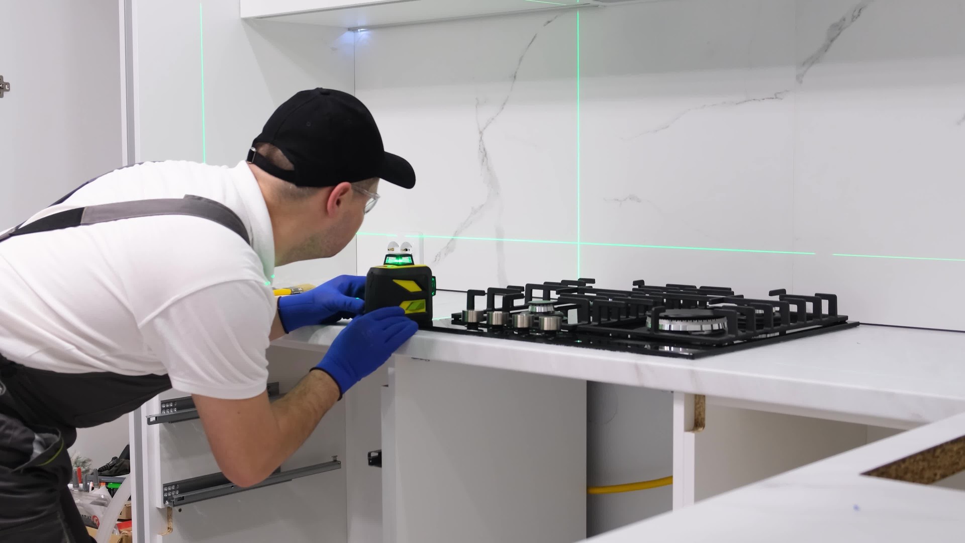A worker installs a new gas stove and measures with a laser. Renovation in a new building.